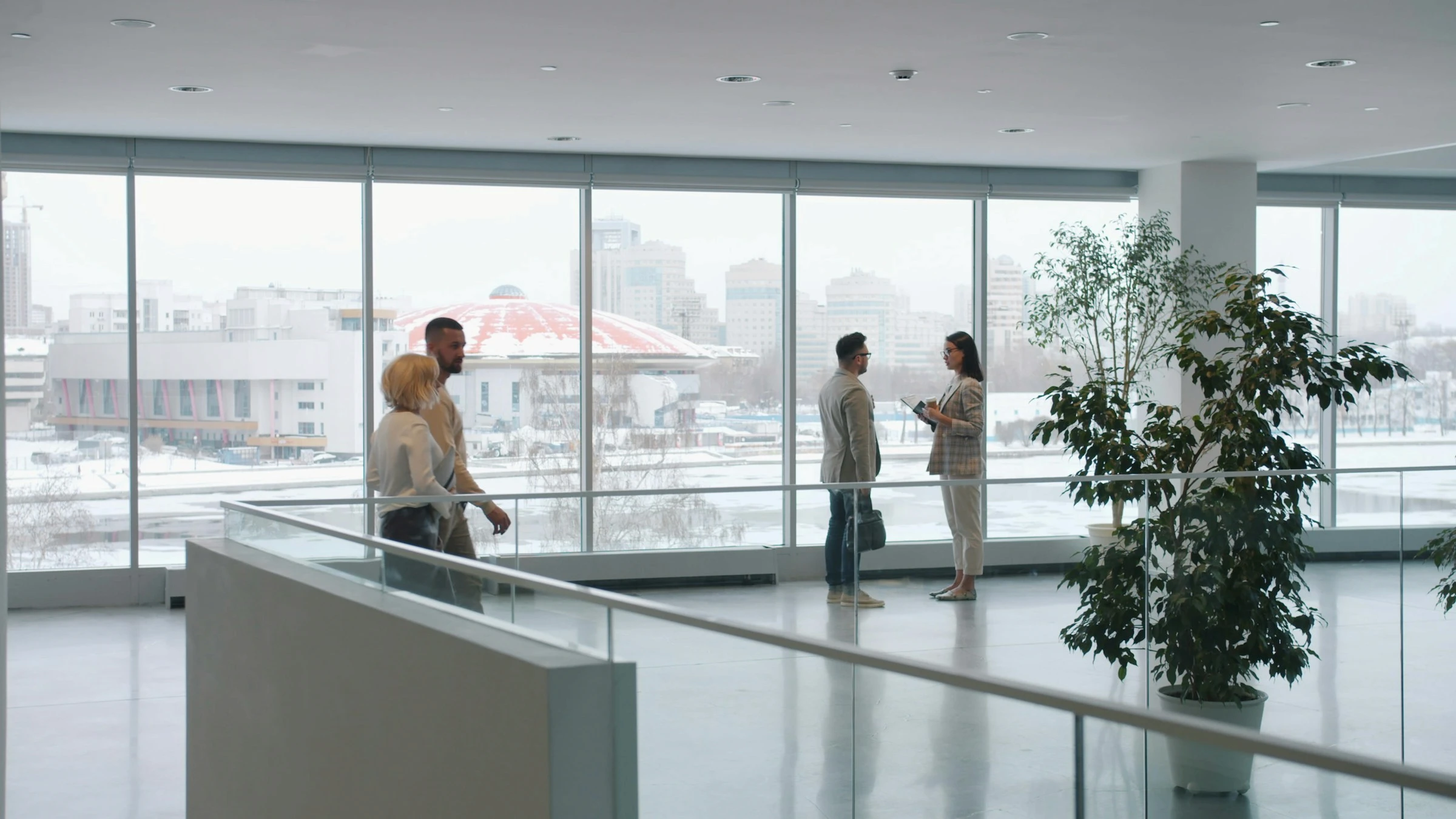 People in conversation within an expansive glass architectural environment